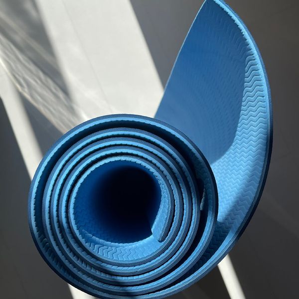 A cozy and clean corner of a room with a yoga mat rolled out.