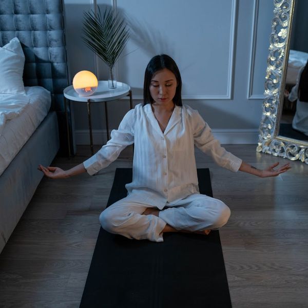 Person meditating peacefully on a mat in a quiet, serene environment.